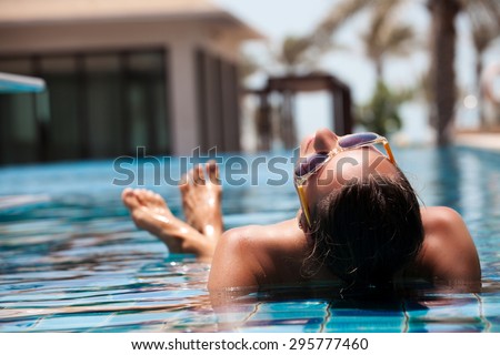 Portrait of sexy cheerful woman relaxing at the luxury poolside.  Girl at travel spa resort pool. Summer luxury vacation.