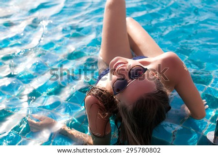 Portrait of happy young female enjoying in the luxury swimming pool. Girl at travel spa resort pool. Summer luxury vacation.