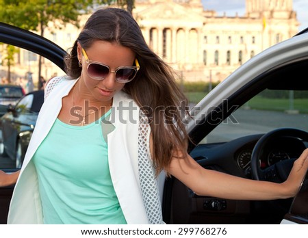 Gorgeous woman staying near her luxury vehicle. Summer road trip traveler concept from Berlin, government building Reichstag, Germany, Europe.
