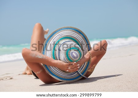 A sun-kissed woman relaxing on the exotic beach in a bikini on sunny summer day. Woman in bikini lying in the sand.