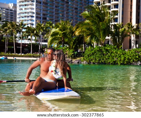 Holidays, vacation, love and friendship concept - smiling couple having fun swimming in surfboard, tropical summer holiday vacation in Hawaii.