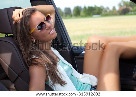 Happy beautiful woman in new car, relaxing.