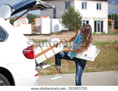 Young woman with luggage. Happy woman taking off suitcases from the car trunk.