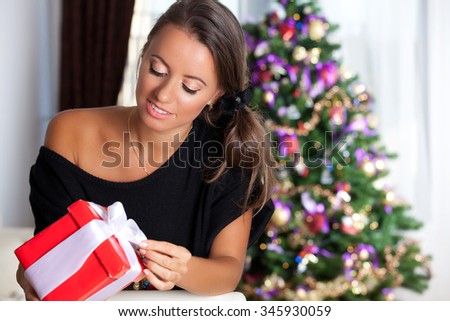 Portrait of a smilling brunette woman with gift box. Christmas, winter, happiness concept.