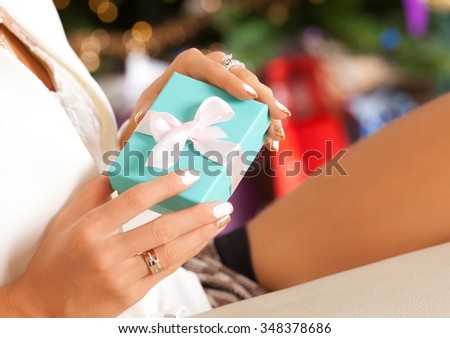 Time for gifts - small gift box in the hands of a woman indoor. Holidays, people and celebration concept.