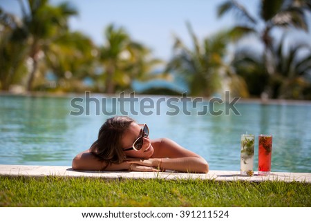 Female beauty enjoying her summer vacation at swimming pool with mojito cocktails. Girl at travel spa resort pool. Summer luxury vacation.