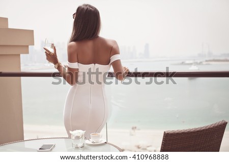 Luxury travel vacation woman with champagne glass looking at view on Dubai famous travel destination. Elegant young lady wearing sexy dress on holidays. Travel concept. (soft focus)