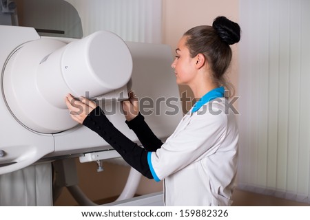 A female doctor operation an x-ray machine in a clinic medical lab with a patient