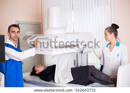 A male doctor and a nurse operation an x-ray machine in a clinic medical lab with a patient
