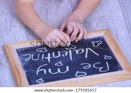 Child hands on a paper size chalkboard saying Be my valentine no face