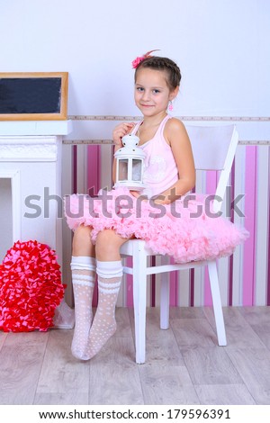 A girl in pink tutu skirt dress in a pink room with beautiful decorations and a blank board for notes sitting on a white chair