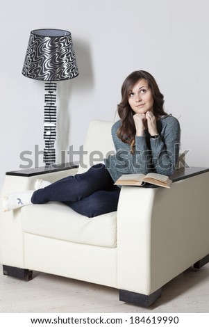 Young attractive woman relaxing in armchair with a good book