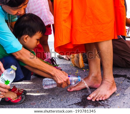SARABURI, THAILAND - JUL 21 2013 :  Unidentified child washing monk\'s feet by pouring water from plastic bottle in Tak Bat Dok Mai or Flower Offering Ceremony on July 21 2013, Saraburi, Thailand