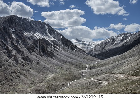 Rocky walls of mountains rising along winding river and road