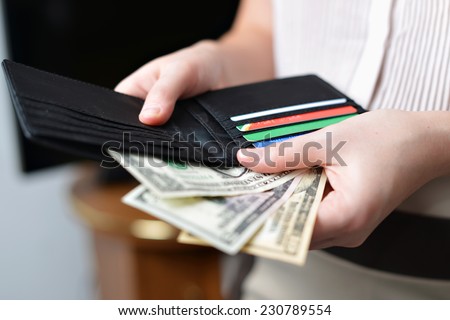 Black purse with money in woman`s hand