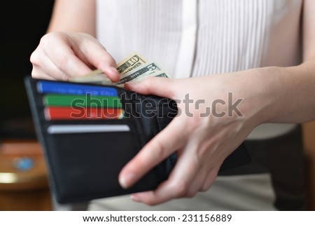 Black purse with money in woman`s hand