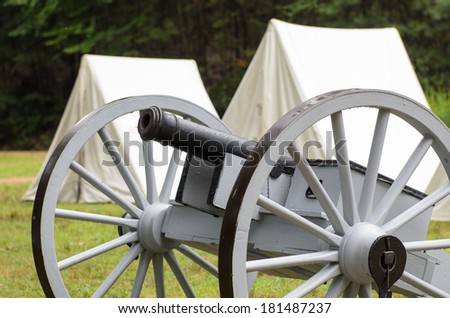 Vintage civil war era cannon and canvas army tents.