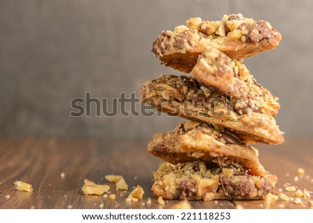A stack of chocolate toffee nut cookies on dark wood table.