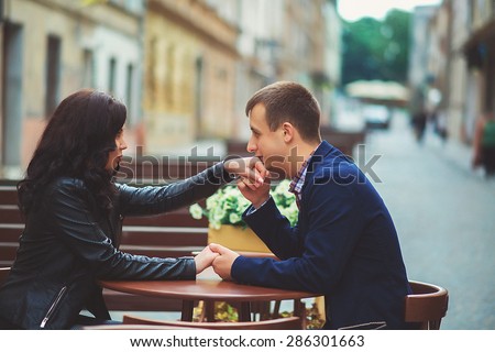 Man kissing a woman\'s hand at a summer cafe