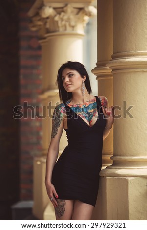 beautiful girl in a black dress stands near architectural structures neckline
