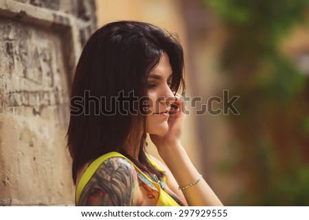 A beautiful woman in a yellow dress, tattoos, posing for photos architecture in Lviv