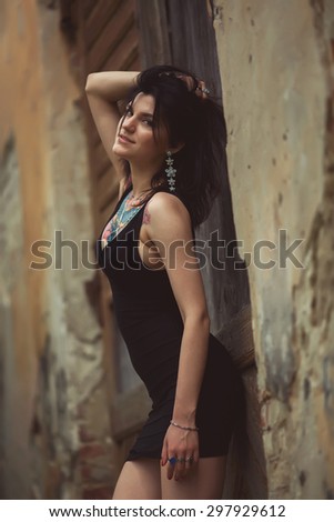 beautiful girl in a black dress stands near architectural structures, posing