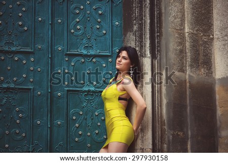 A beautiful woman in a yellow dress, tattoos, leaned his shoulders against the wall