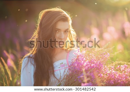 Beautiful young girl, happy, holding lavender, in a field on sunset. walking field. Soft focus, close-up