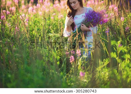 Beautiful young girl, holding lavender in a field on sunset. walking field. Soft focus