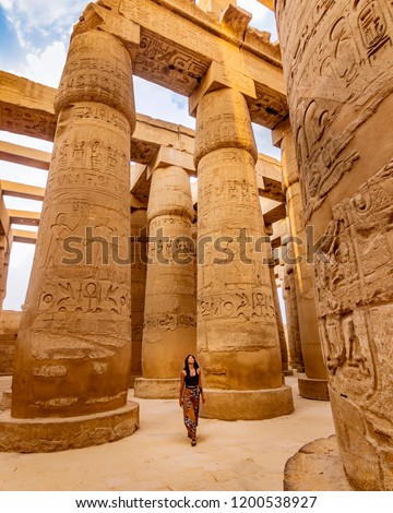 EXPLORING EGYPT - Young female traveller wandering through ancient Karnak Temple. Beautiful Egyptian landmark with hieroglyphics. Travelling woman adventuring around the world. Luxor, Egypt