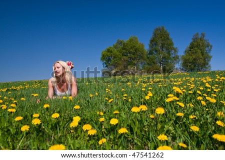 young woman lying on a dandelion meadow