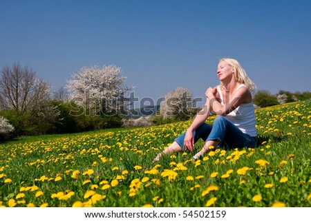 young woman lying on a dandelion meadow