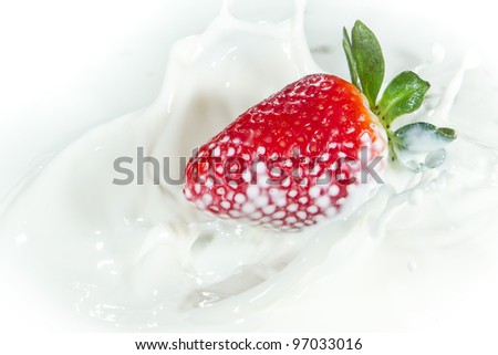delicious fresh strawberry falling into splashing milk