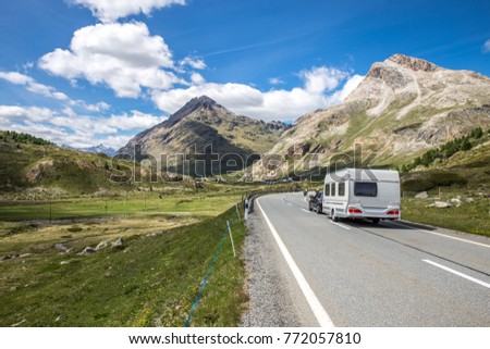A caravan on the way to the vacations. Swiss mountains with a cloudy sky