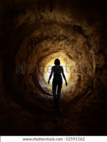Lonely woman is walking through dark tunnel to the light