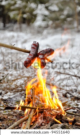 Sausages on the stick grilled in the fire. Winter camp.