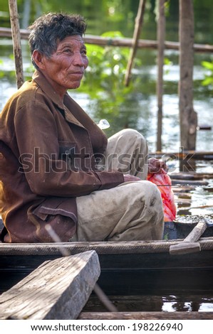 AMAZONIA, PERU - DEC 28: Unidentified Amazonian indigenous man cooking fish over a wooden raft, on December 28, 2009, in Peruvian Amazonia, Loreto, Peru, South America