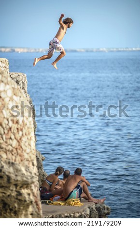 Menorca - September 8: Young man jumping from a cliff into the sea, on september 8, 2014, in Menorca, Balearic Islands, Spain