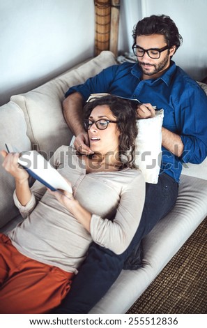 Young couple reading book on couch at home
