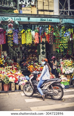 HANOI, JUNE 15, 2015: A girl on her motorbike waiting in front of a store in the street selling artificial flowers, on June 15, 2015, in Hanoi, Vietnam