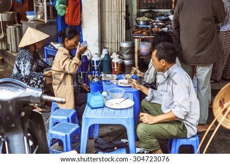 HANOI, VIETNAM - APRIL 8, 2015: Customers have their meal on the street stall on April 8, 2015 on Hanoi. Vietnamese people love to socialise when they eat.