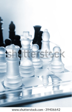 Black and white transparent pieces of chess on chess board made of glass