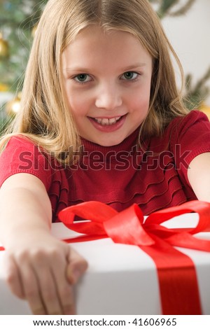 Pretty blond hair girl in red sweater holding big white gift box with red ribbon