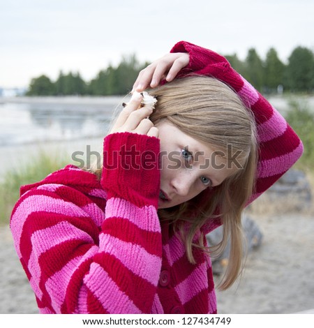 Girl holding sea shell up to ear listening to ocean