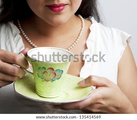Woman holding vintage porcelain tea cup with saucer