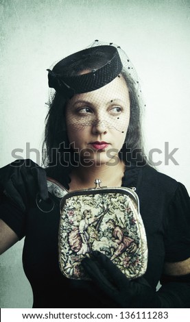 A beautiful woman dressed in vintage clothing pulling pistol out of her purse