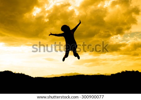 Silhouette little Girl jumping on sunset background