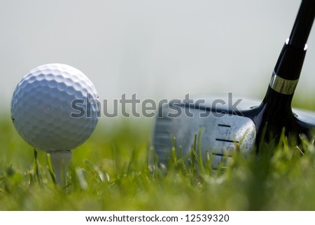 Driver club and white golf ball on small tee. Ready to swing