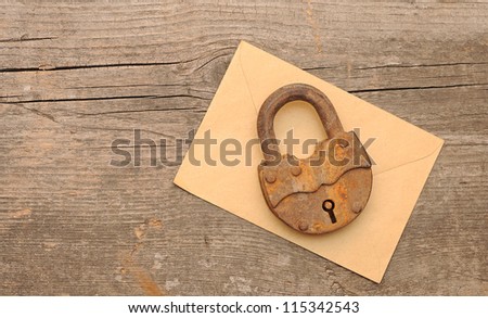 Old padlock on yellow envelope over  wooden background. With copy space