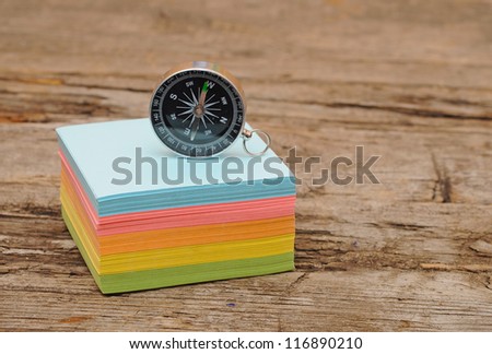 colorful post it note block with compass on wood table